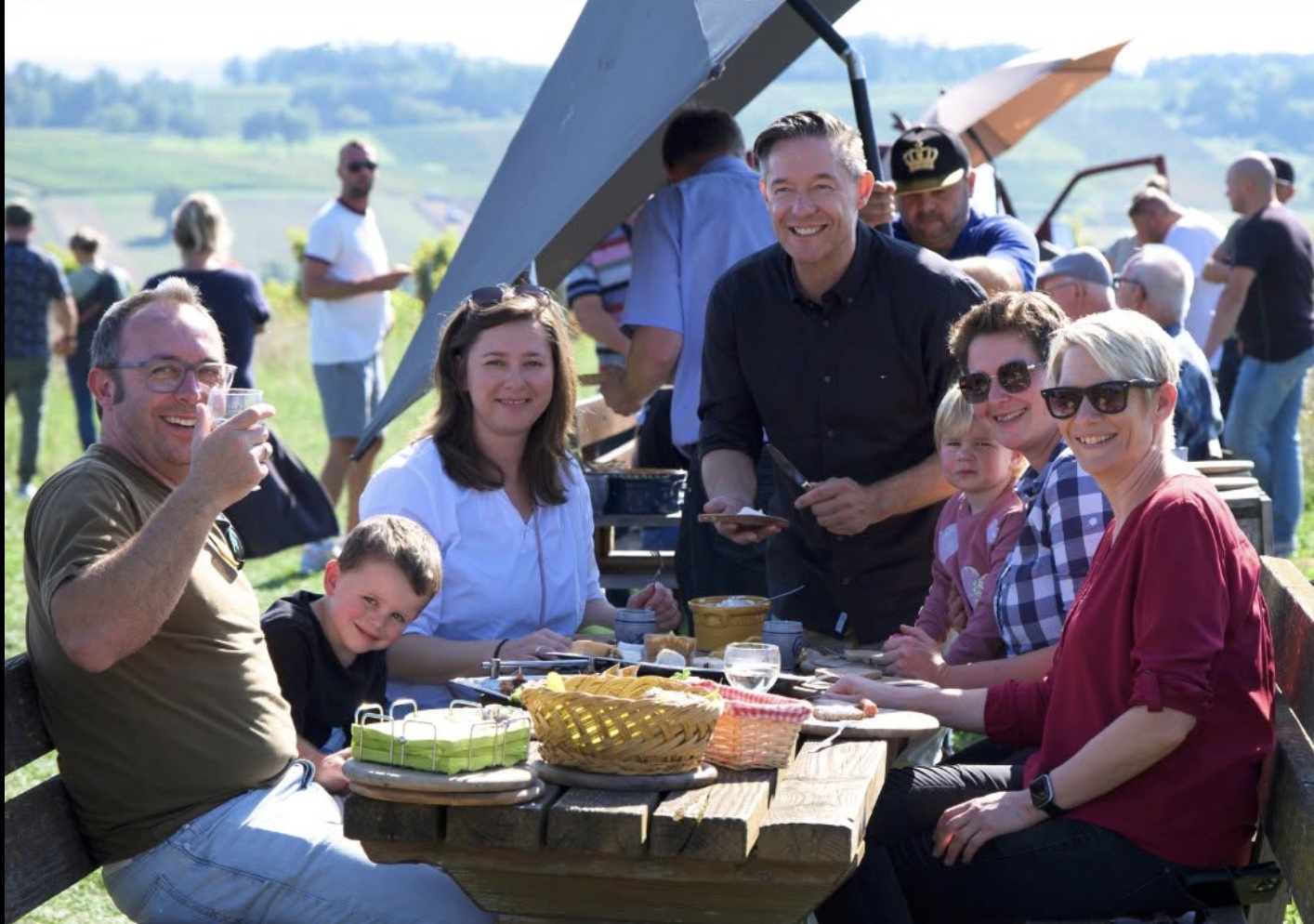 Gesellige Runde mit Erwachsenen und Kindern beim gemeinsamen Essen und Wein im Freien