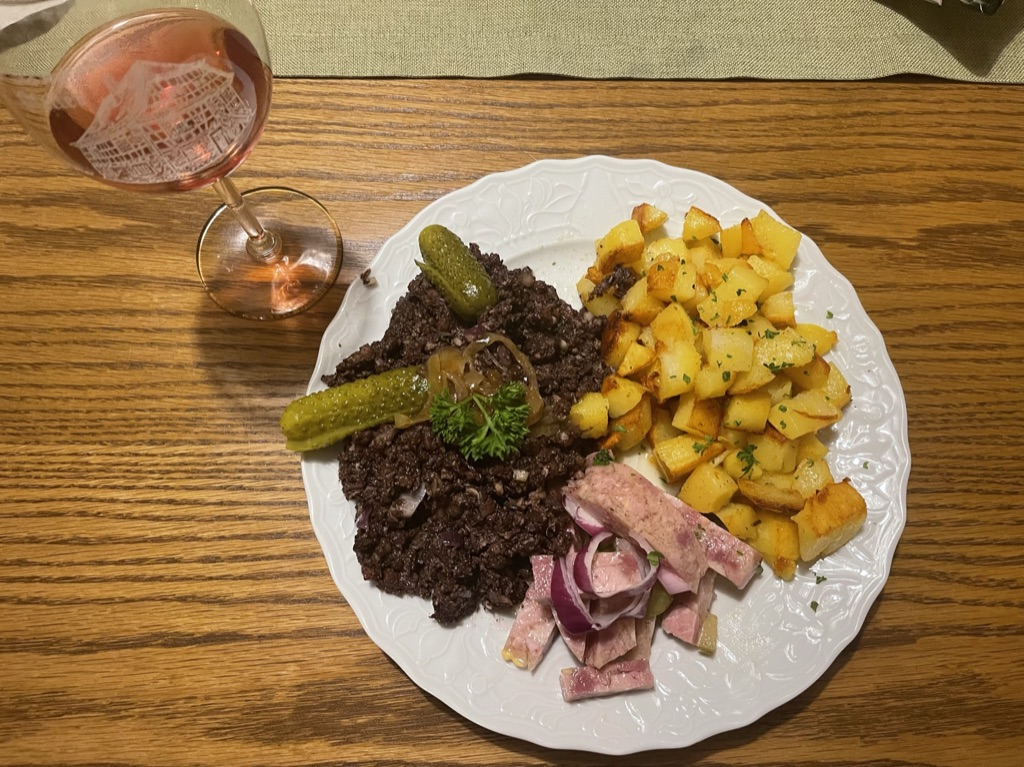 Ein Glas Rosé und ein herzhaftes Gericht mit Bratkartoffeln auf dem Tisch in der Weinstube